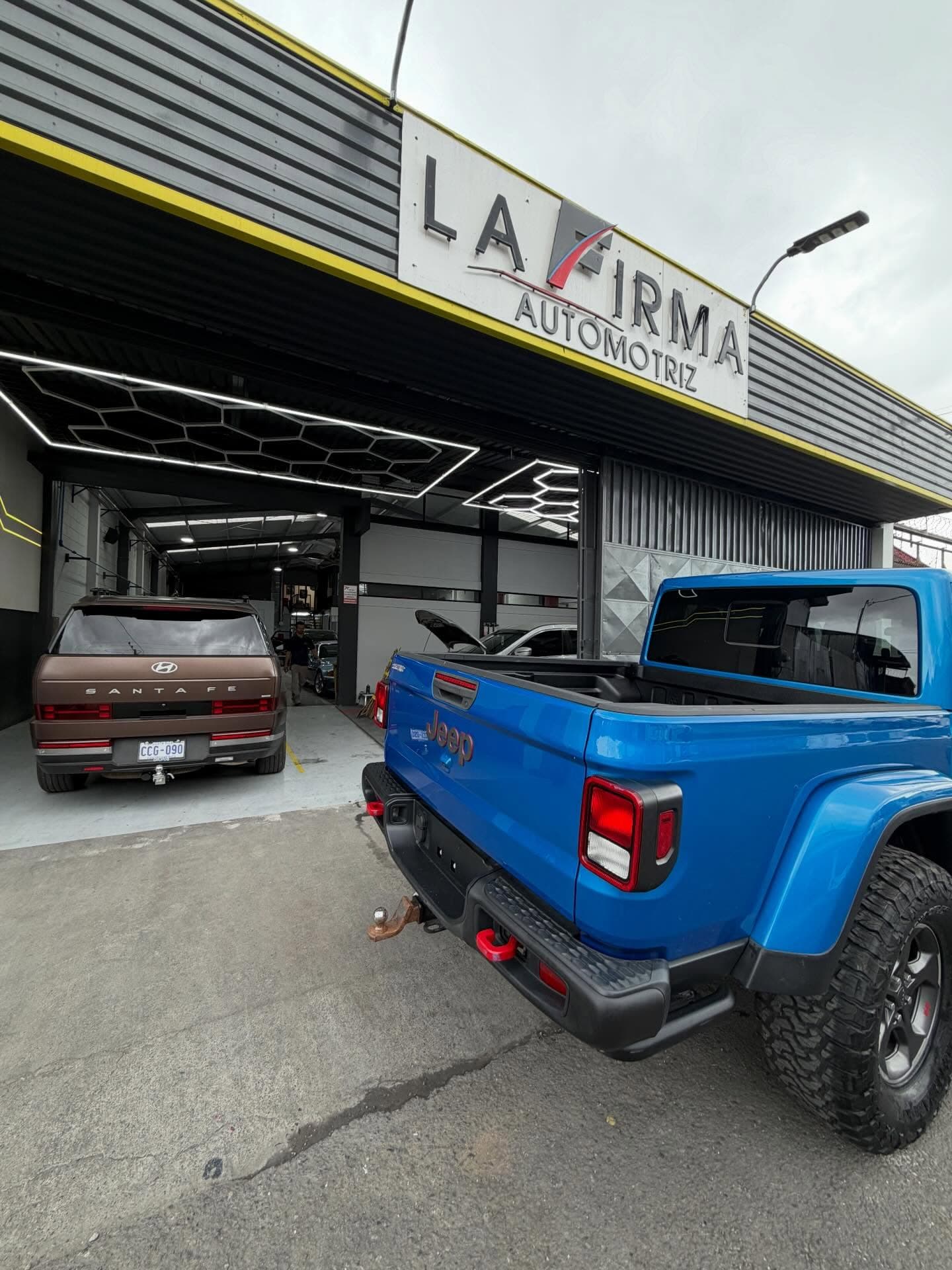 Fachada del taller La Firma Automotriz con vehículos en el área de recepción