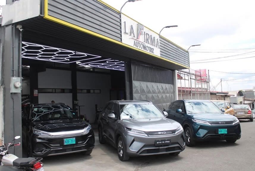 Entrada del taller La Firma Automotriz con vehículos en el área de trabajo